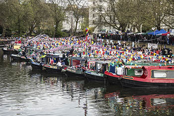 Brightly decorated boats, with bunting, lined up alongside each other at a previous Canalway Cavalcade event, Little Venice, London.