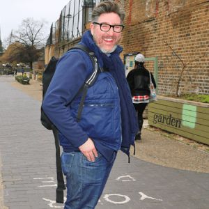 Dick Vincent, National Towpath Advisor, Canal & River Trust. Pictured on a towpath in blue anorak and jeans, with a dark blue rucksack. He has dark brown hair, glasses and a short greying beard.