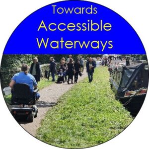Logo: Towards Accessible Waterways. The text in yellow on blue above a picture of a wheelchair user amongst many others on a towpath. There is a wide grass verge, and some narrowboats moored alongside.