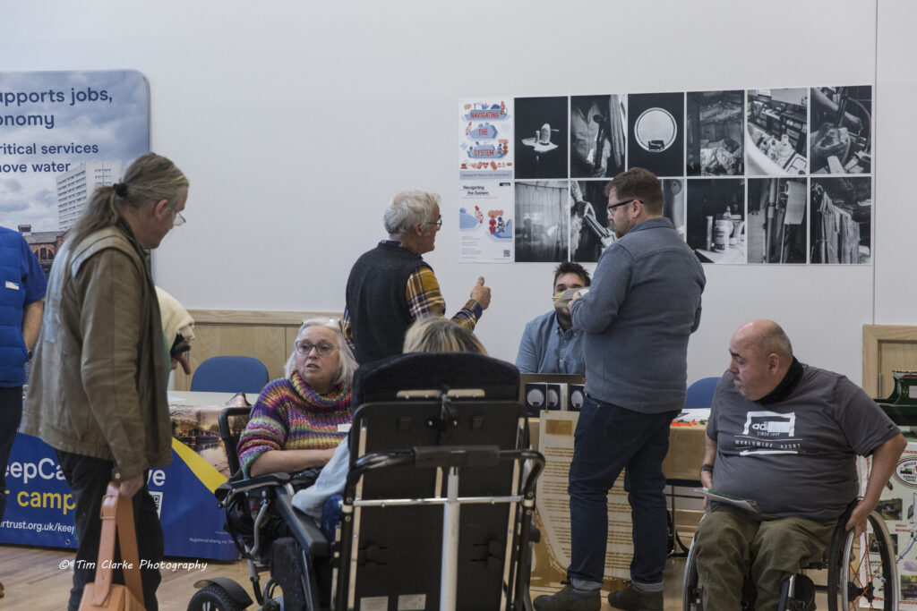 A group of delegates gathered and chatting around the "Navigating the System" exhibitor stand.