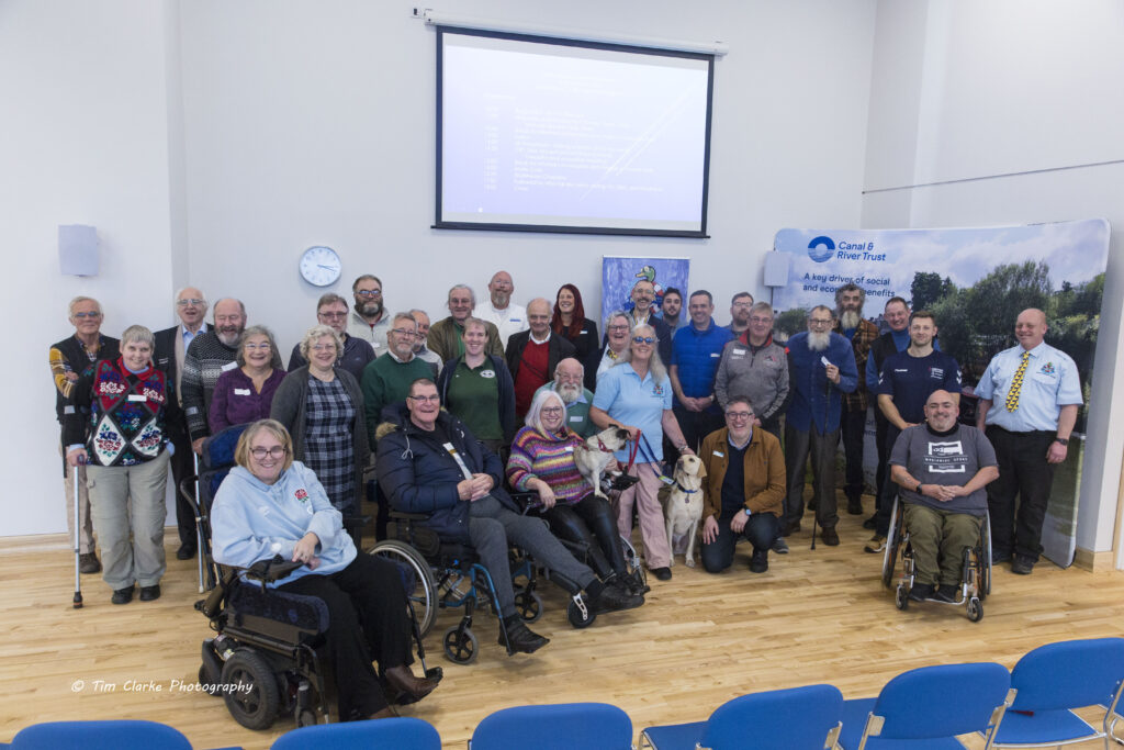 A photo of 33 of the attendees - and two assistance dogs! A Yellow Lab (Guide Dog) and Fawn Pug Cross (Hearing Assistance Dog).