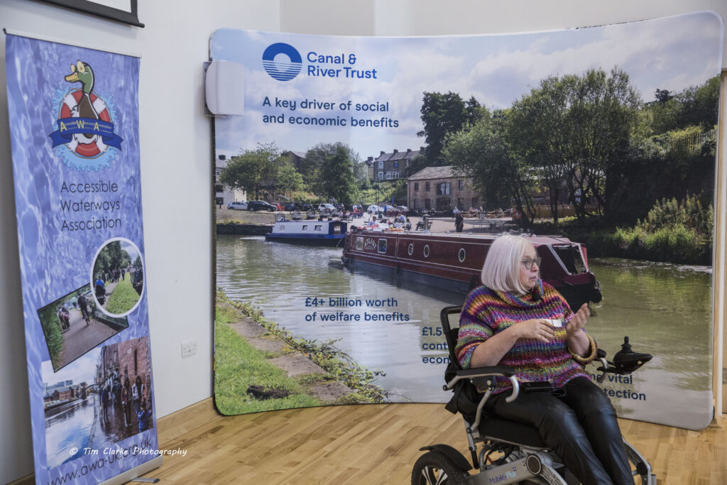 Liz Humpheys, a lady with shoulder length silver hair, presenting from her wheelchair.