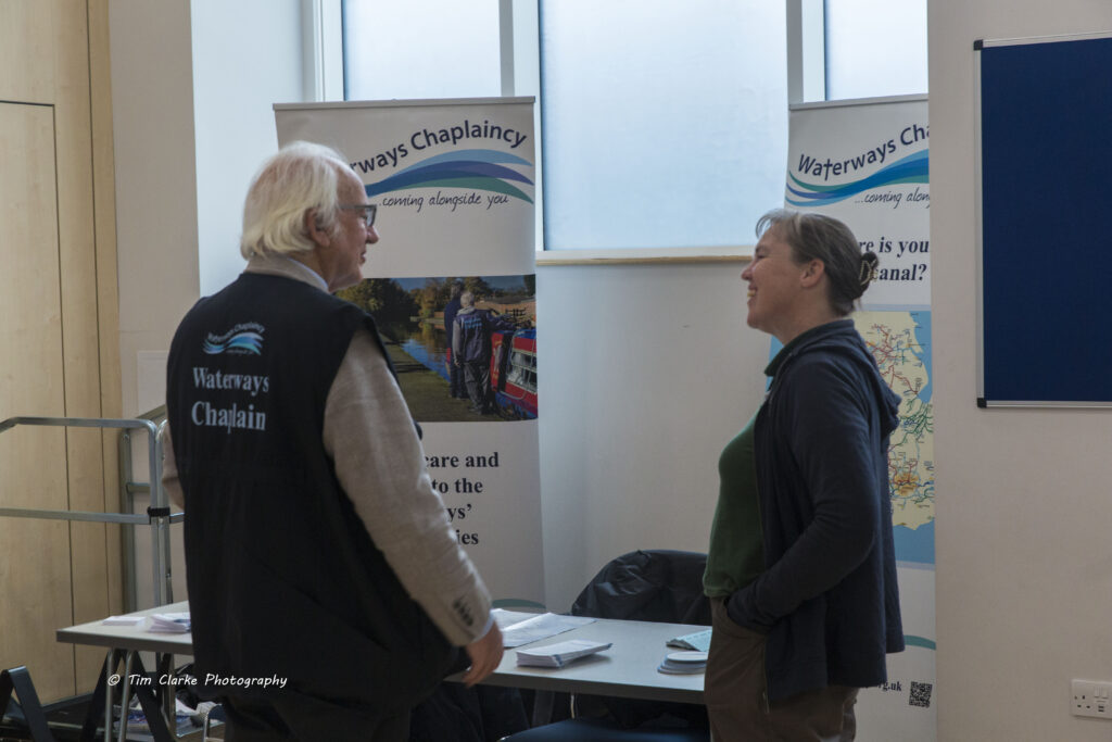 Sliver haired Richard Alford, wearing his Waterways Chaplain gilet at their stand chatting to Ali Cannon from Bruce Boats.